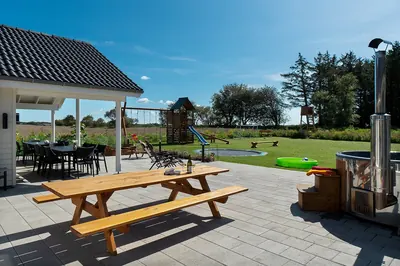 Den overdækkede terrasse med langbord og udendørs badetønde